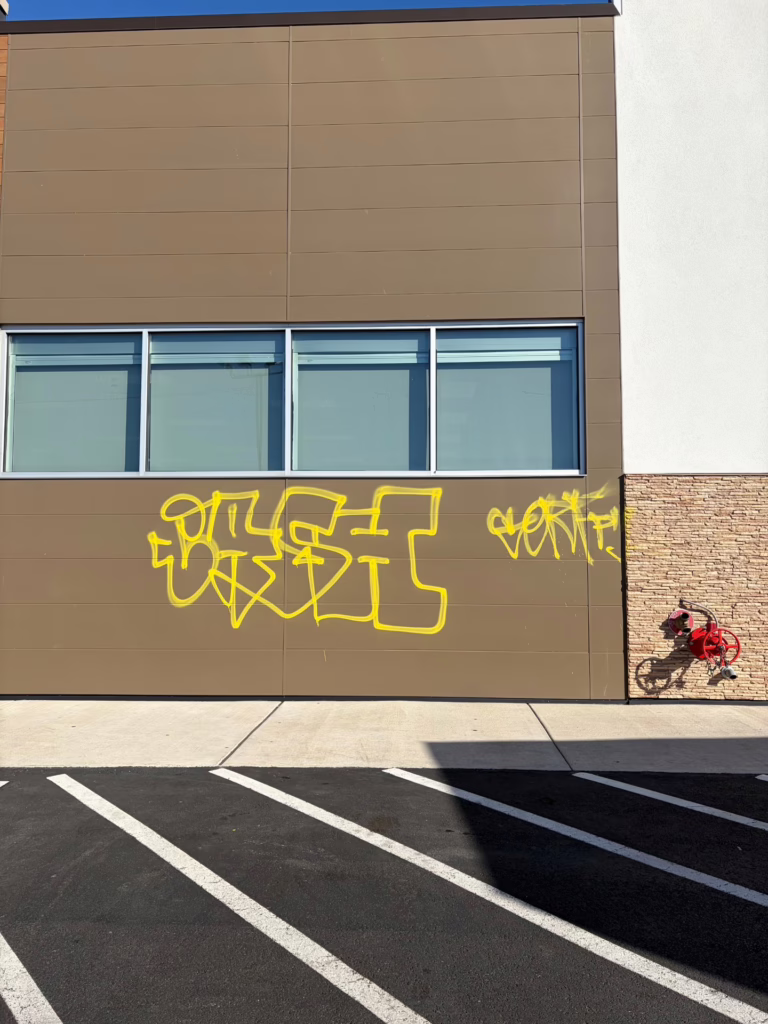 Powder Coated Metal Building Surface with Yellow Spray Paint Graffiti